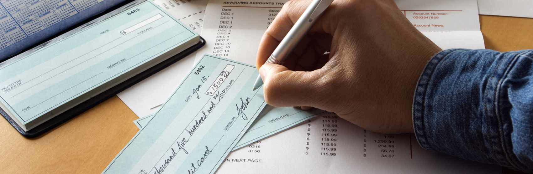 Picture of bills and person writing a check